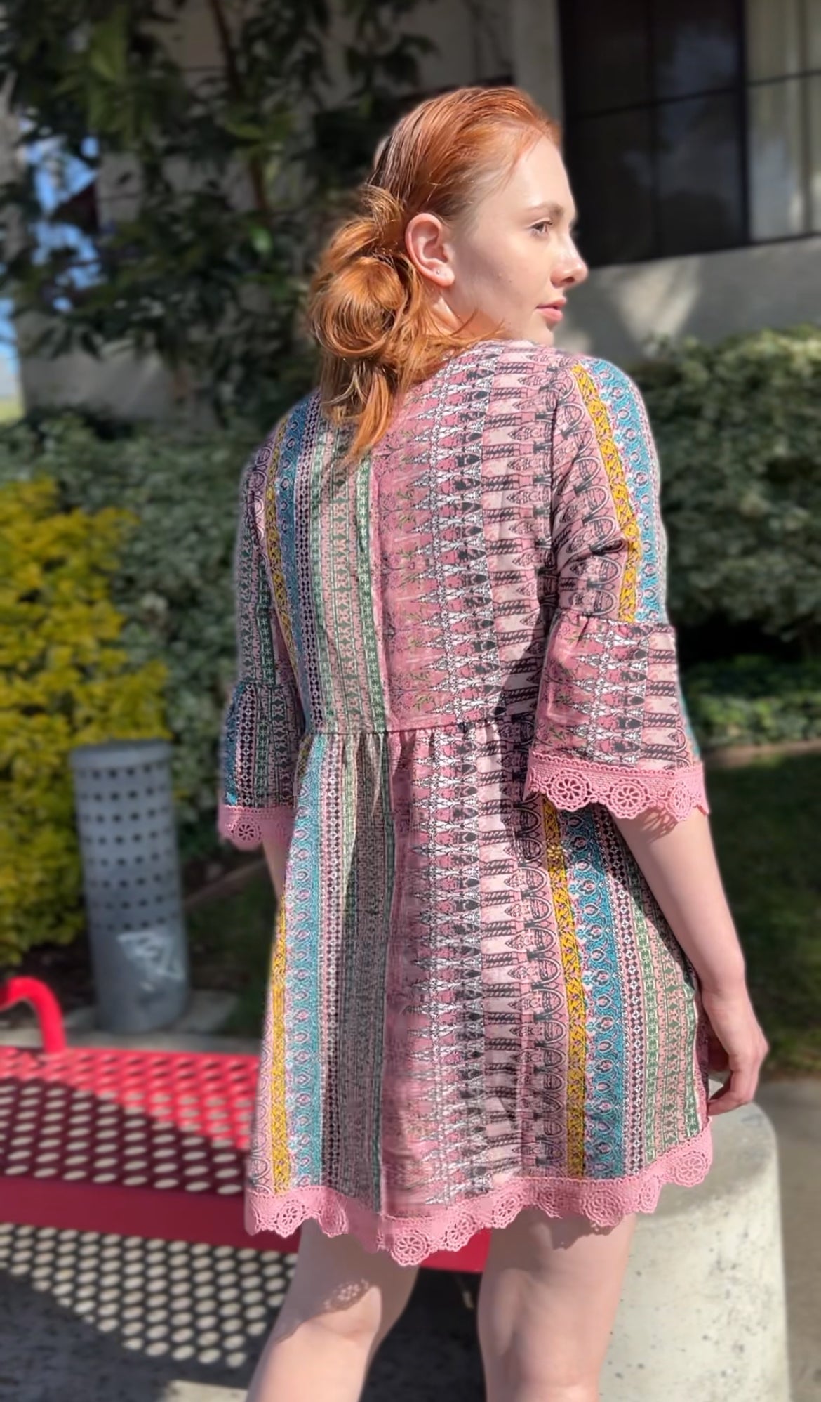 Woman in Boho Chic Pink Striped Mini Dress with Lace Trim – Flowy & Feminine Facing backwards