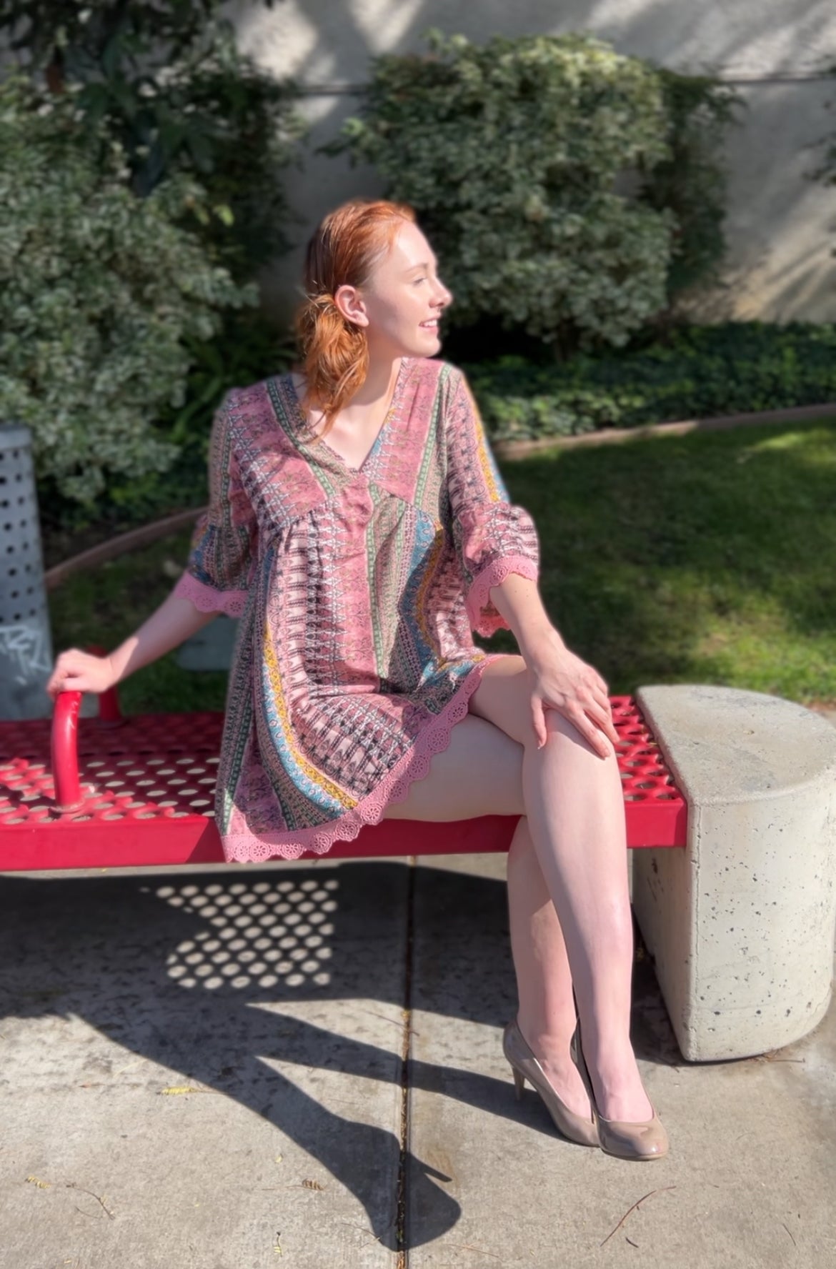 Woman in Boho Chic Pink Striped Mini Dress with Lace Trim – Flowy & Feminine sitting down Facing forward
