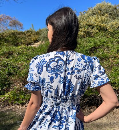 Woman in Blue Floral Puff Sleeve Midi Dress with V-Neck facing backwards