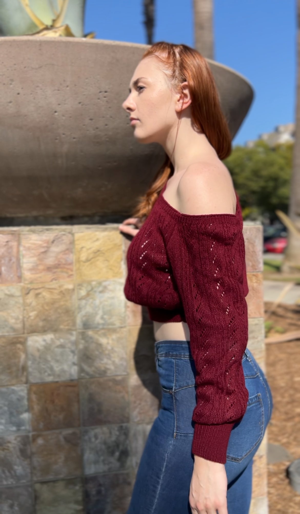 Woman in Burgundy One Shoulder Sweater facing sideways up close