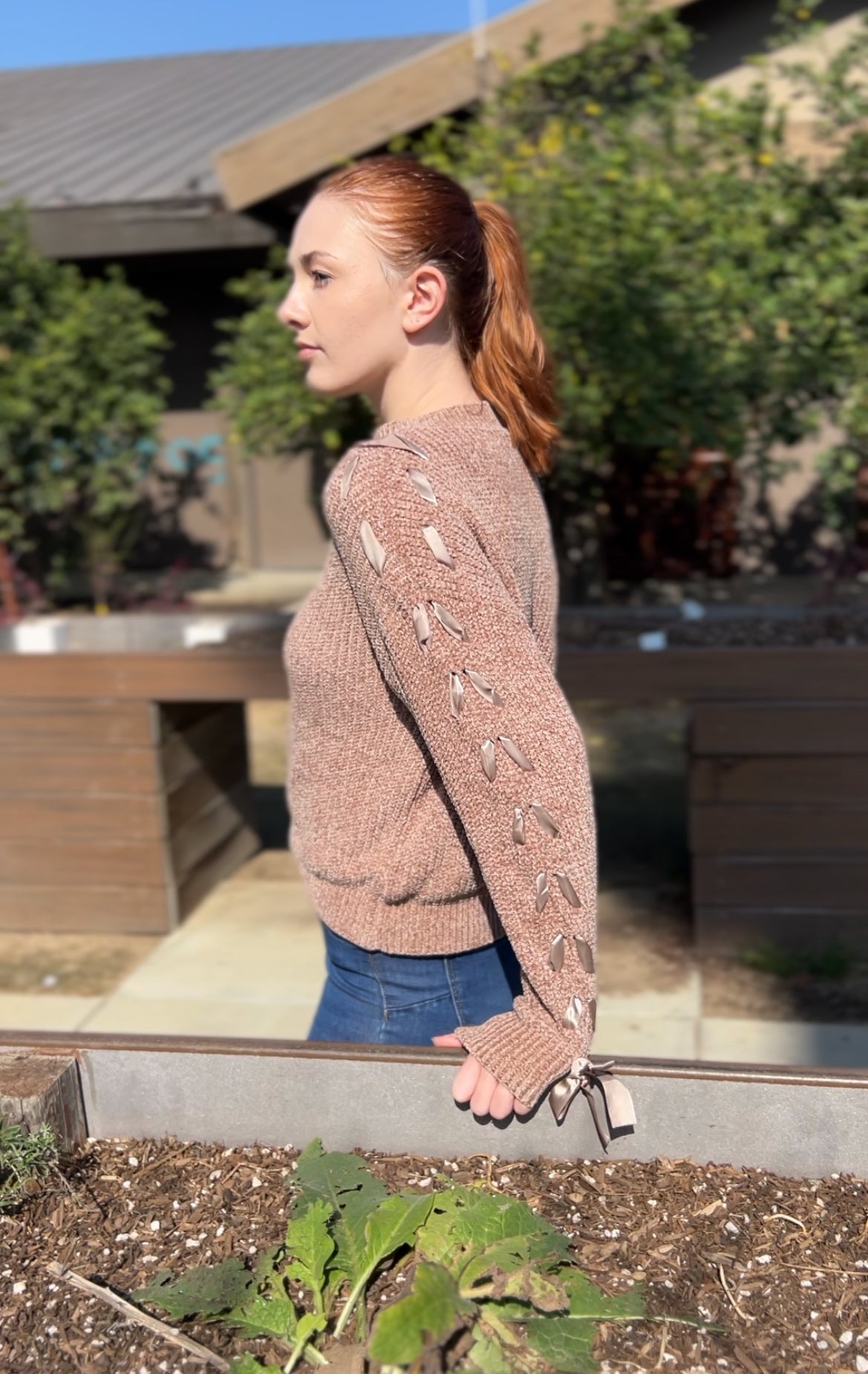 Woman in Khaki Lace Up Sleeve Knit Sweater facing sideways up close