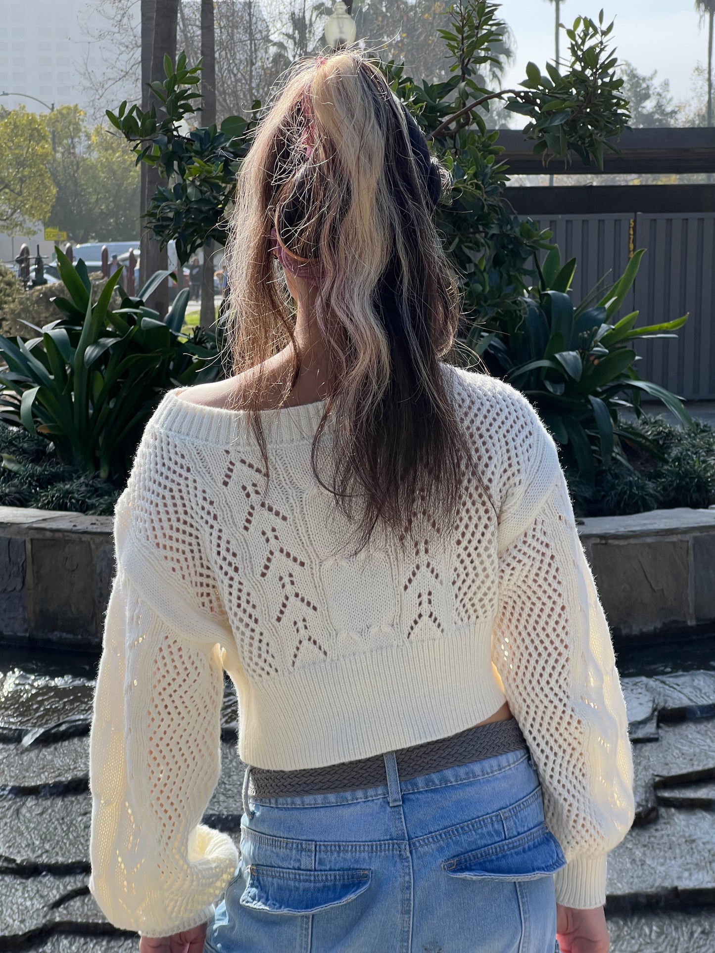 Woman in Neutral Beige Cropped Knit Top facing backwards up close 