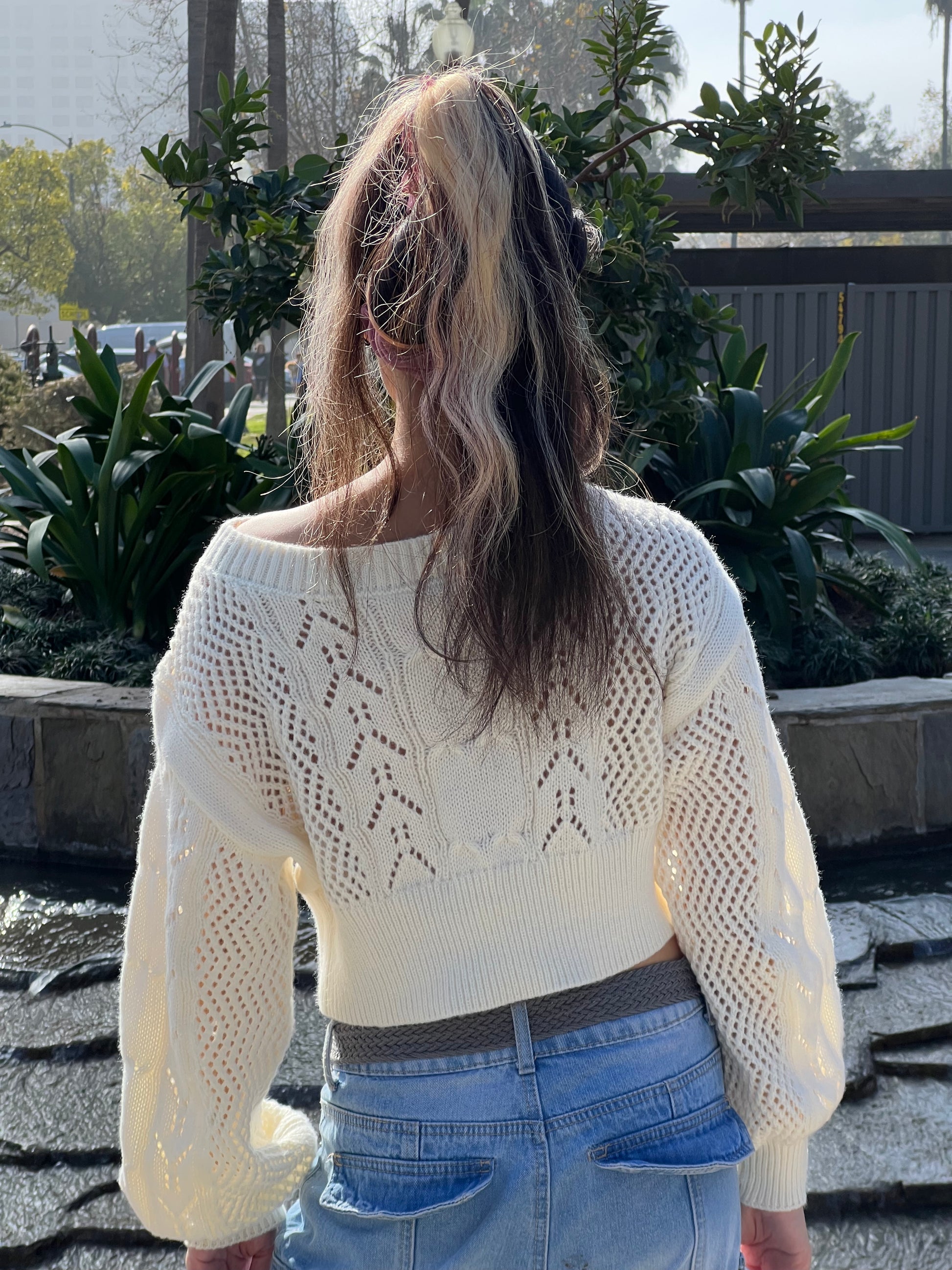 Woman in Neutral Beige Cropped Knit Top facing backwards up close 
